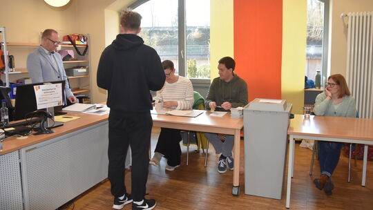 Eine Szene vom sonnigen Sonntag: Ein Wähler gibt seine Wahlbenachrichtigung ab und erhält den Wahlschein. Wie er haben es auch T