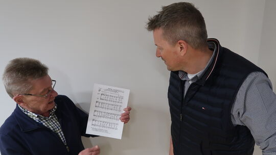Chorleiter Berthold Bätzing (links) erläutert Ortsbürgermeister Steffen Kappes den Text des Siegsteig-Liedes.