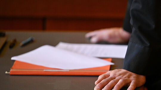 Akten liegen auf einem Tisch: Bei einer Verständigung im Prozess gegen den Koblenzer (Schrott)Immobilien-Händler würden sich die