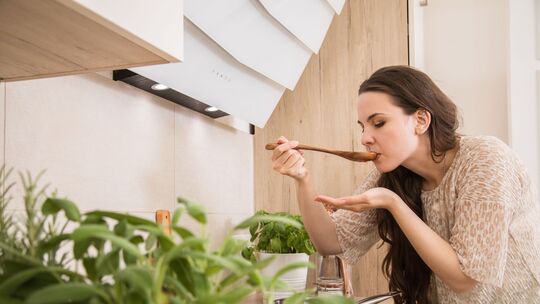 Eine Frau kostet eine Suppe, Käuter im Vordergrund