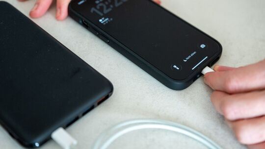 Eine Frau schließt ein iPhone an eine Powerbank an