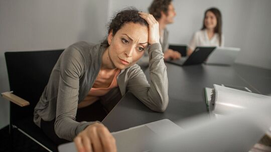 Frau sitzt grübelnd vor ihrem Laptop im Büro Frau sitzt grübelnd vor ihrem Laptop im Büro