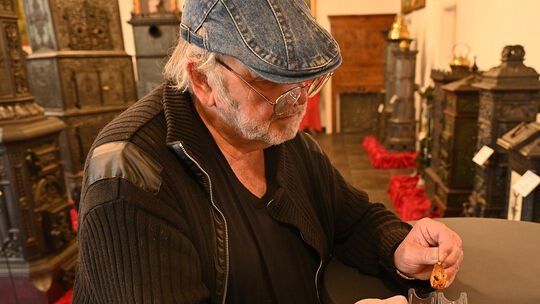 Museumsbetreiber Wolfgang Lengler hat drei kleine Bernstein Exponate in seiner Hand, die vor rund 40 Millionen Jahren entstande