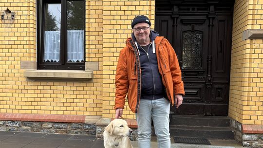 Heiner Trauthig und sein Hund Willi stehen vor dem Hauptgebäude der Eremitage.