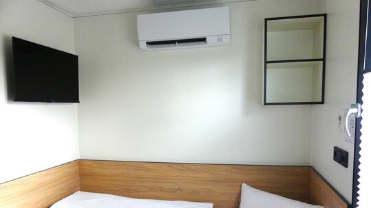 Einblick in ein Roatel-Zimmer: Kompakte Gemütlichkeit auf nur acht Quadratmetern, ausgestattet mit TV und Klimaanlage.