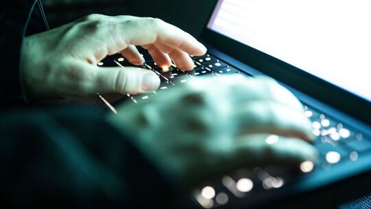 Eine Person tippt auf einer beleuchteten Laptop-Tastatur