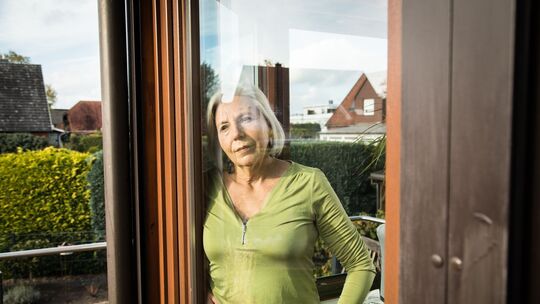 Eine Frau blickt aus einem Fenster auf einen Garten