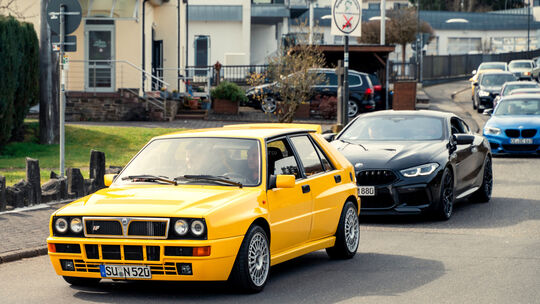 Ein kanariengelber Lancia Delta HF Integrale führt die Blechlawine durch Nürburg zum Kreisel an der Nordschleifen-Zufahrt.