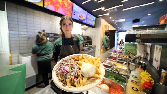 Eine Mitarbeiterin von Frittenglück in Koblenz präsentiert den Taxiteller.