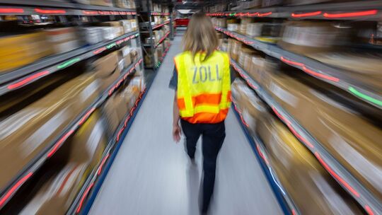 Eine Zollbeamtin läuft durch ein Paketlager