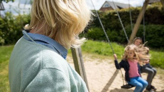 Eine Frau beobachtet Kinder beim Schaukeln