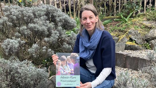 In ihrem Kräutergärtchen mit 140 verschiedenen Kräutern zeigt Diana Kaiser ihr Workbook, das sie für die Selbstbearbeitung und