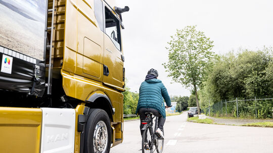 Symbolbild: Ein Fahradfahrer fährt im toten Winkel eines Lkw. Diese Konstellation kann schnell gefährlich werden.
