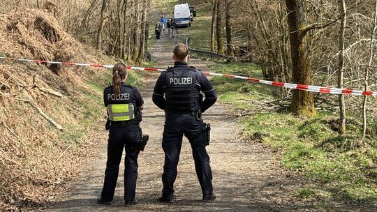 Kräfte der Polizei sind in einem mit Flatterband abgesperrten Bereich eines Waldes im Einsatz. Bei einer Müllsammelaktion wurde