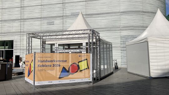 Ein Banner auf dem Zentralplatz kündigt an: Die Handwerksmesse Koblenz startet bald.