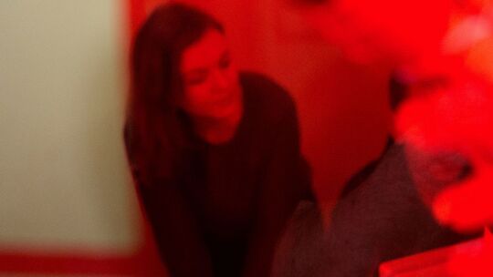 Eine Frau sitzt hinter einer rot bemalten Scheibe