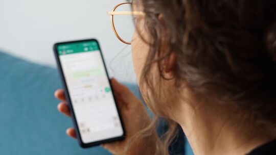 Eine junge Frau liest eine Nachricht auf einem Smartphone