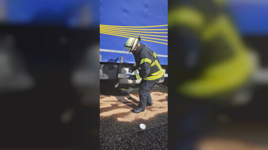 Ein Feuerwehrmann streut Bindemittel auf ausgelaufenen Diesel auf der Fahrbahn der B41 bei Rüdesheim.