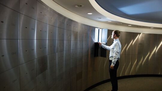 Ein Sparkassenmitarbeiter legt Papiere in ein Schließfach