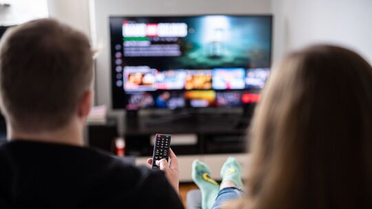 Paar sitzt vor einem Fernseher mit Streamingdiensten