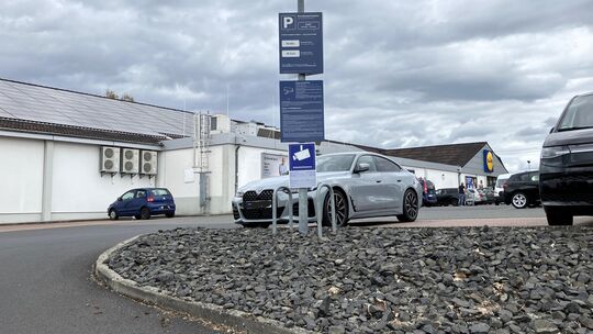 Die untere Einfahrt zum Lidl-Parkplatz in Hachenburg von der Koblenzer Straße aus: An dem Mast hängt eine Tafel des Betreibers P