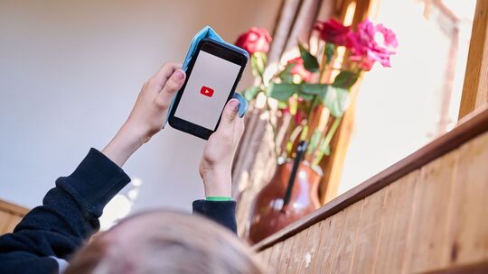 Junge öffnet auf seinem Smartphone die App von YouTube