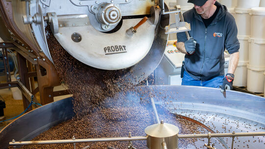 Frisch geröstete brasilianische Kaffeebohnen fallen hervor, als Arne Großmann die Luke der Rösttrommel öffnet.
