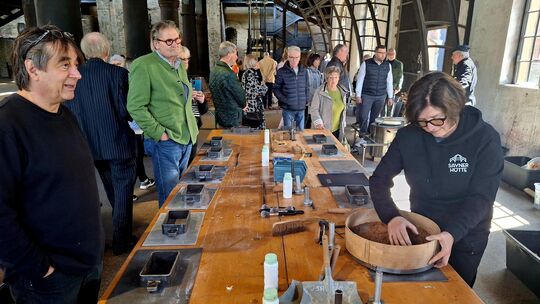 Besucher beobachten Museumsleiterin Barbara Friedhofen (rechts) beim Formen des Sayner Hüttentalers.