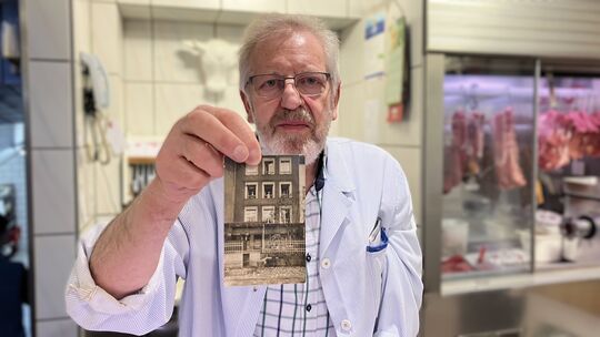 Metzgermeister Siggi Schmitz zeigt ein Foto, auf dem das Haus abgebildet ist, bevor die Gaststätte eröffnet wurde