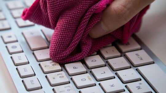 Ein Mann reinigt eine Tastatur mit einem Mikrofasertuch