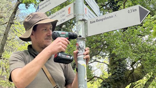 Marc Bremmer schraubt die Wanderwegsbeschilderung zum Rheingrafenstein ab.