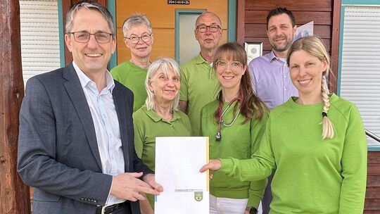 Bürgermeister Oliver Götsch (von links) übergibt den Förderbescheid an das Team des Allgemeinarztzentrums Freilingen mit Ursula