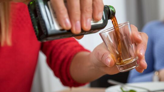 Frau schenkt ein Glas Schnaps ein