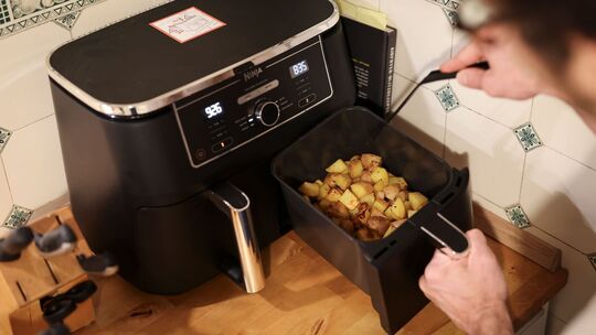 Mann kocht mit einem Airfryer Mann kocht mit einem Airfryer