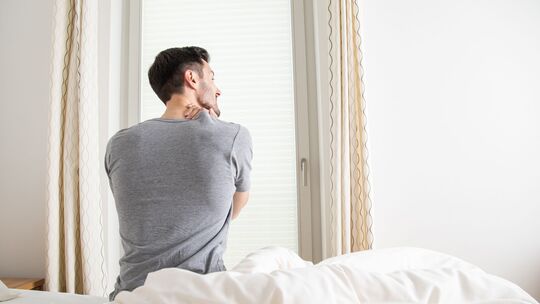 Ein Mann hält sich seine verspannten Muskeln am Nacken Ein Mann hält sich seine verspannten Muskeln am Nacken