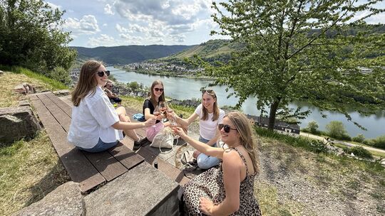 Die Freundinnen Sara, Hannah, Jule und Chantal stoßen mit einem Glas Wein auf den gelungenen Tag in den Zeller Weinbergen an.