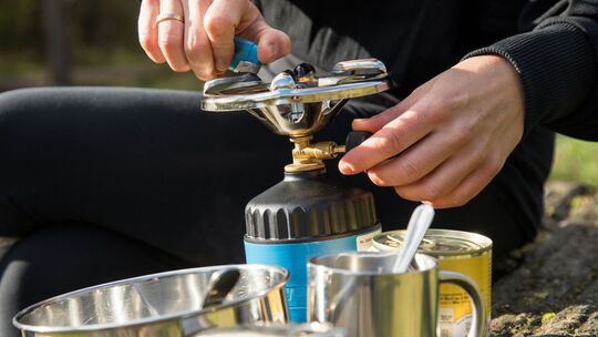 Frau bereitet Essen auf einem Campingkocher zu
