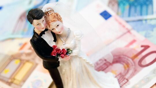 Eine Brautpaarfigurine steht auf Geldscheinen Eine Brautpaarfigurine steht auf Geldscheinen