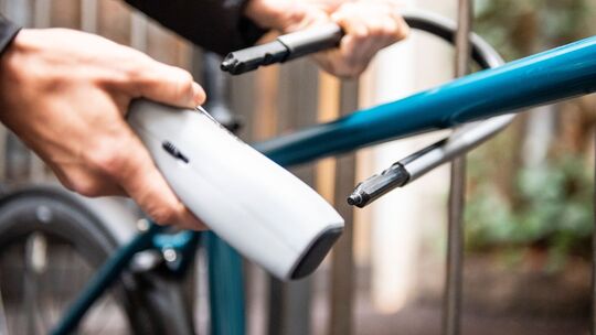 Person schließt ein Fahrrad an einem Zaun an