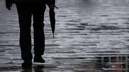 Ein Passant geht mit Regenschirm in der Hand durch Mainz