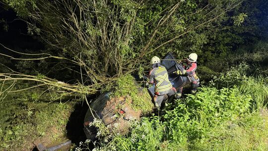 Einsatzkräfte sichern den Unfallwagen, der bei Ellweiler von der Straße abgekommen ist und an einem Baum zum Stillstand kam.