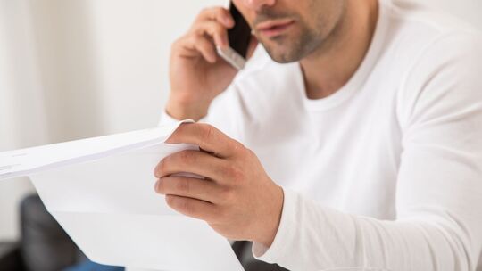 Mann telefoniert mit einem Brief in der Hand