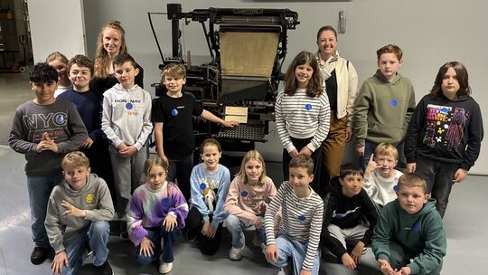 Die Klasse 4c der Astrid-Lindgren-Schule in Rengsdorf vor einer historischen Druckmaschine.