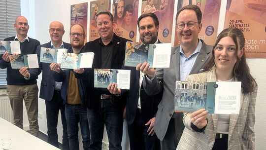 Die Anwesenden zeigen das druckfrische Programm mit den aufgeführten Konzerten und Theaterstücken