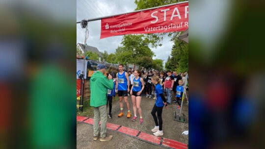 Moderator Heinz Hofmann kündigt den Zwei-Kilometer-Lauf sowie Felix und Lena Müller von der LLG Hunssrück (blaue Trikots) an, di