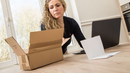 Frau schaut in den Karton einer Online-Lieferung Frau schaut in den Karton einer Online-Lieferung