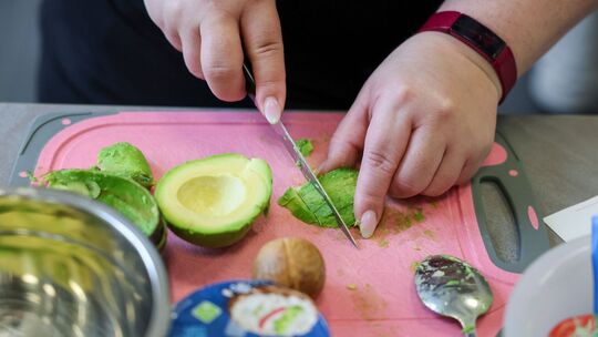 Eine übergewichtige Frau schneidet Avocado Eine übergewichtige Frau schneidet Avocado