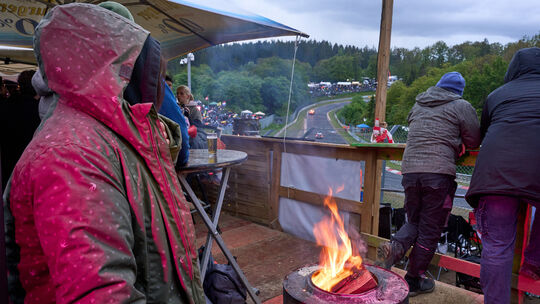Zuschauer des 24-Stunden-Rennens auf dem Nürburgring wärmen sich bei kaltem Wetter an einem Feuer.