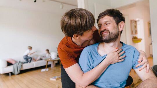 Eltern umarmen sich während Kinder im Hintergrund toben
