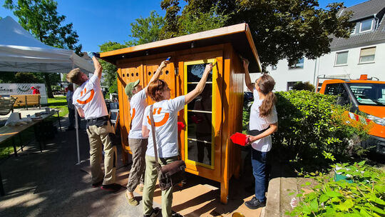 Für das Projekt „Food Sharing Schrank” legten städtische Mitarbeiterinnen und Mitarbeiter mit Pinsel und Farbe letzte Hand an. N